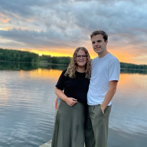 Amanda och Daniel Jennebratt en sommarkväll framför en sjö med solnedgång i bakgrunden